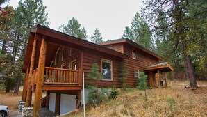 Une cabane en bois dotée d’une véranda, d’un garage et située dans un cadre naturel, au cœur d’une forêt.