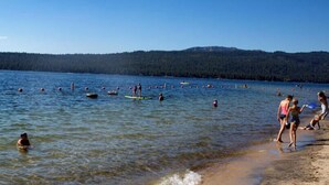 Un lago con gente disfrutando actividades acuáticas, rodeado de un paisaje boscoso.