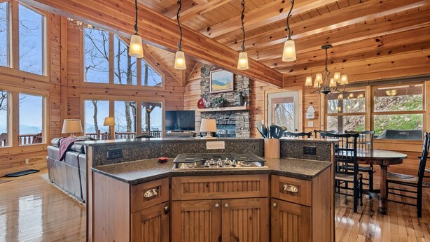 Una cocina amplia con armarios de madera, encimeras de granito y una isla central. Grandes ventanales ofrecen vistas al exterior.