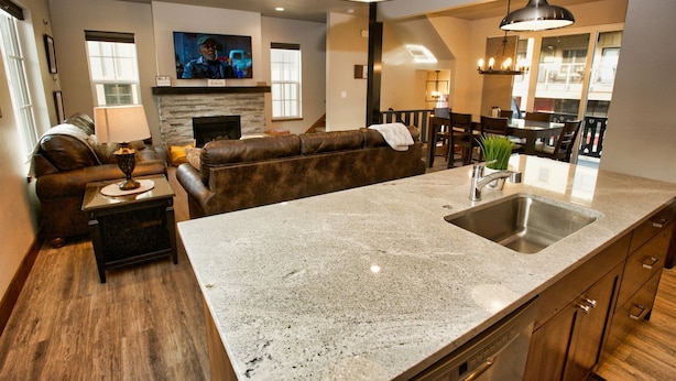 A modern kitchen with a granite countertop, stainless steel sink, and wooden cabinets. - Suite Retreat: Short Walk to Downtown McCall, A/C, Propane Fireplace (McCall)