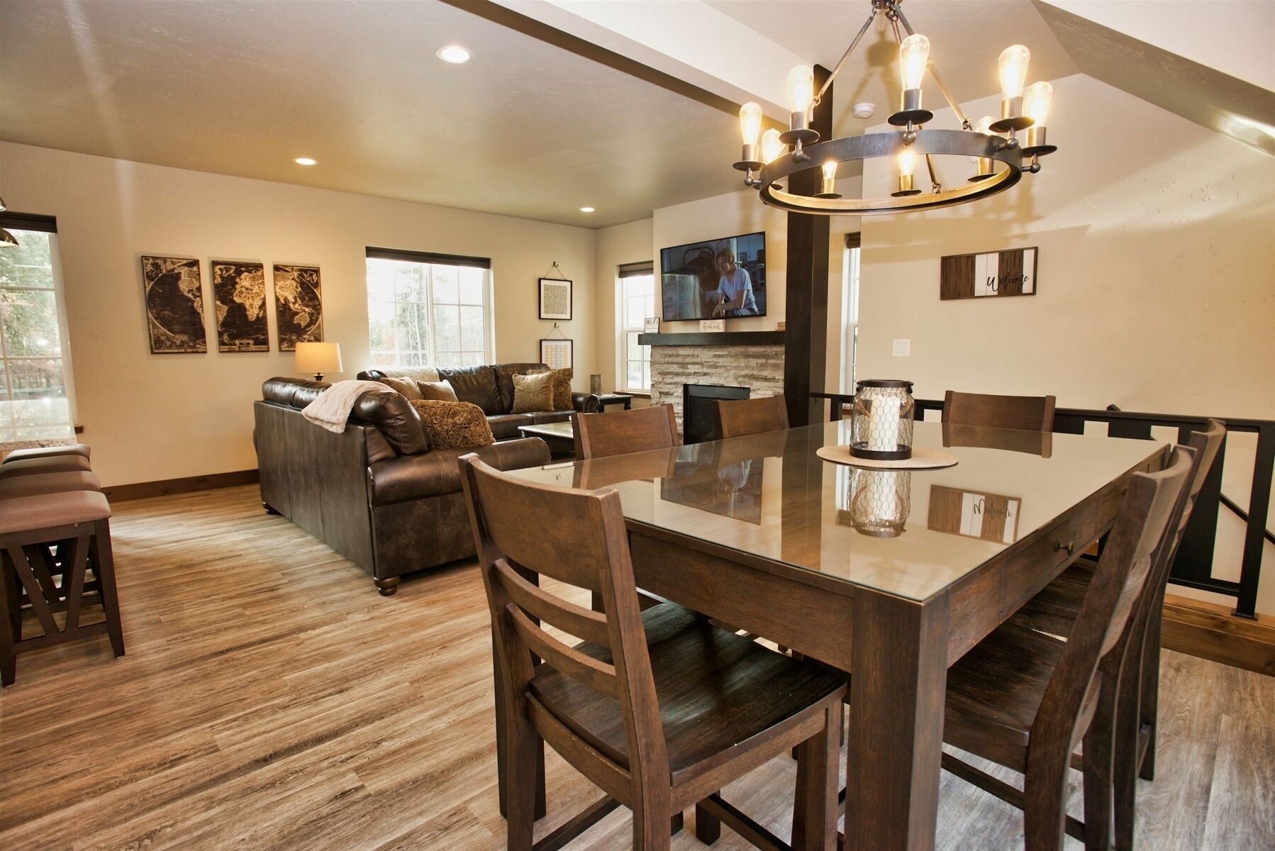 A spacious living room with a large dining table, leather sofa, and a TV mounted on the wall.
