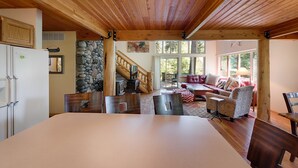 Una habitación amplia con una cama grande, techo de madera, pared de piedra y un rincón de descanso acogedor con chimenea.