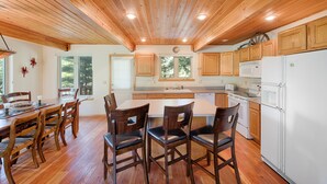 Una cocina amplia con armarios de madera, una isla central y una zona de comedor con sillas de madera.