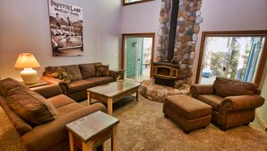 A cozy living room with a stone fireplace, a couch, a coffee table, and a lamp. - Peace in the Pines: Woodland Oasis in Spring Mountain Ranch, Private Hot Tub (McCall)