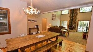 A wooden dining table with benches, a stone fireplace, and a stone wall. - Peace in the Pines: Woodland Oasis in Spring Mountain Ranch, Private Hot Tub (McCall)