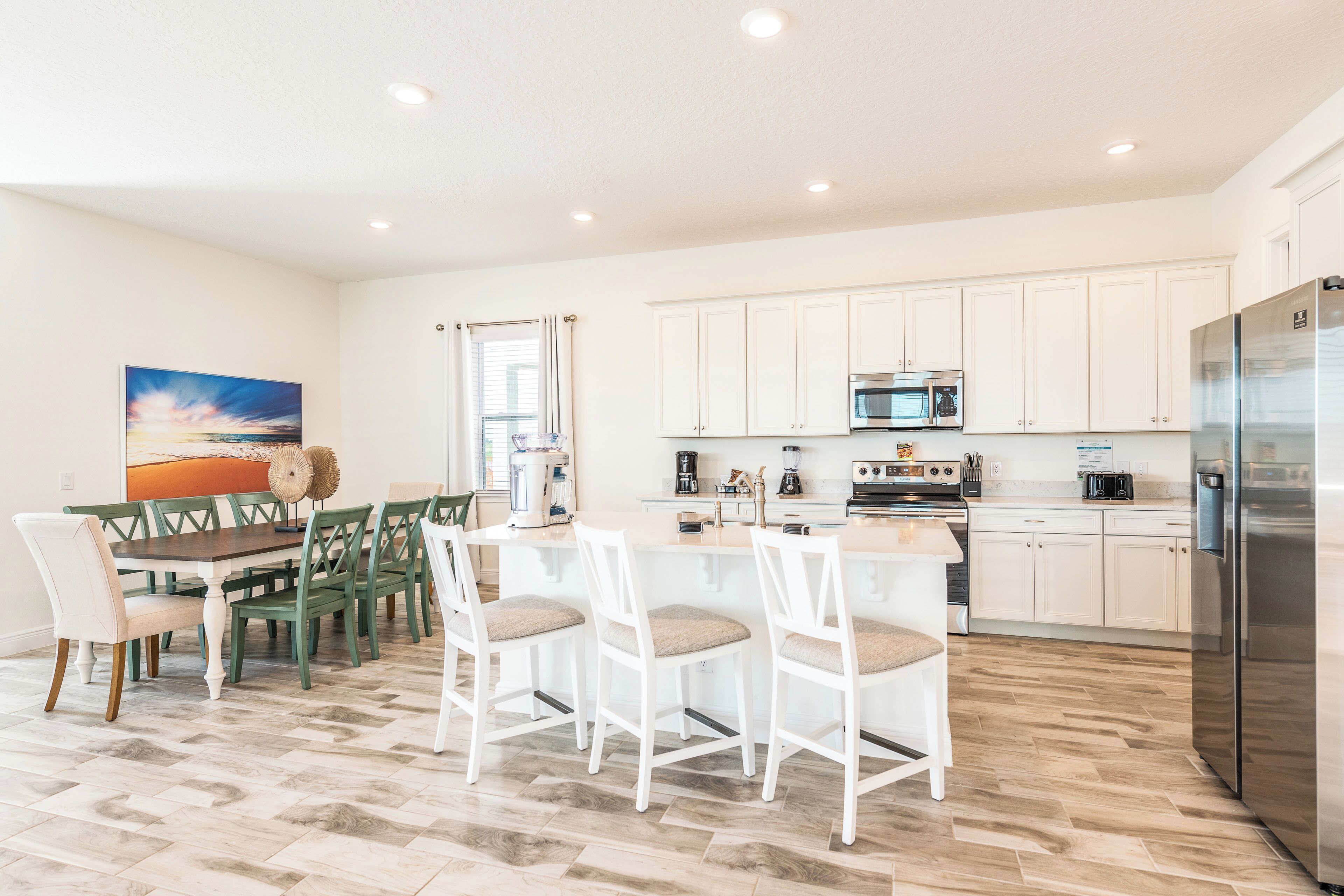 A modern kitchen with white cabinets, stainless steel appliances, and a dining area with a wooden table and chairs.
