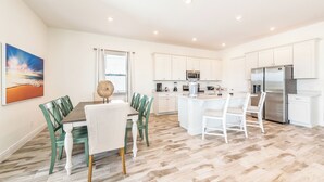 A modern kitchen with white cabinets, stainless steel appliances, and a central island.
