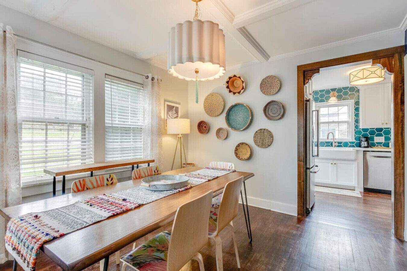 A dining area with a wooden table, chairs, and a decorative wall with woven plates.