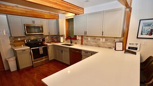Eine moderne Küche mit Holzbalkendecke, Edelstahlgeräten und einer weißen Arbeitsplatte.