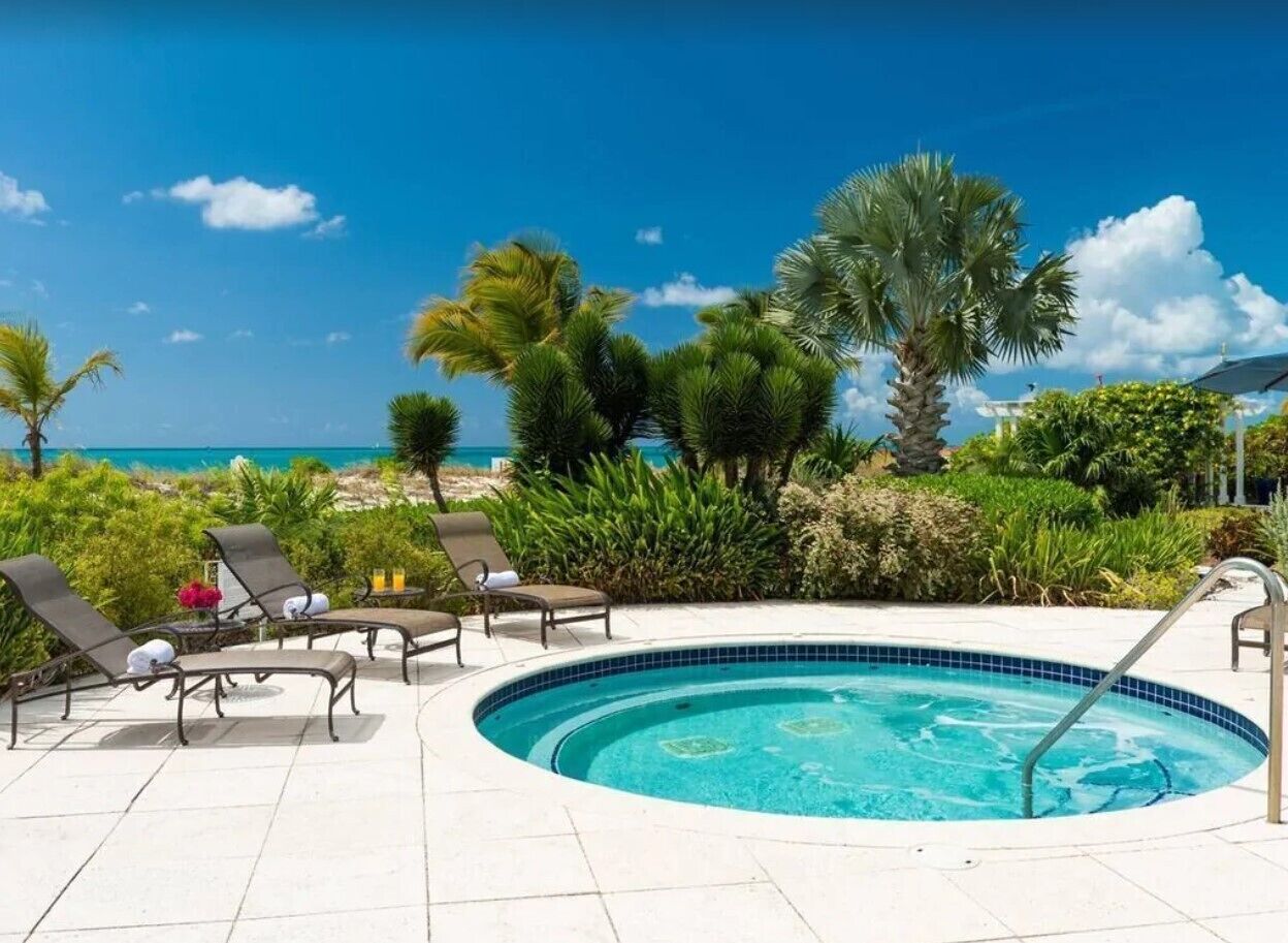 A circular swimming pool with lounge chairs and a view of the ocean.
