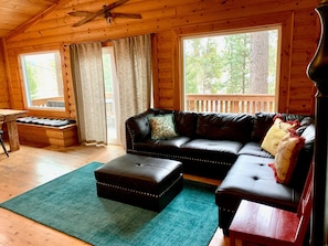 L’intérieur d’un chalet chaleureux, avec un canapé en cuir, un pouf et une table en bois.