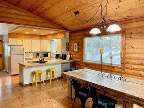 L’intérieur d’un chalet en bois comprend une cuisine, un coin repas et une grande fenêtre.