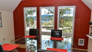 Un salón de conferencias con una mesa de vidrio, detalles en rojo y ventanas amplias que dan a una vista de un lago y montañas.