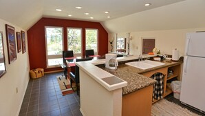Una cocina con una isla central, dos fregaderos, un refrigerador y un comedor con sillas y una mesa.
