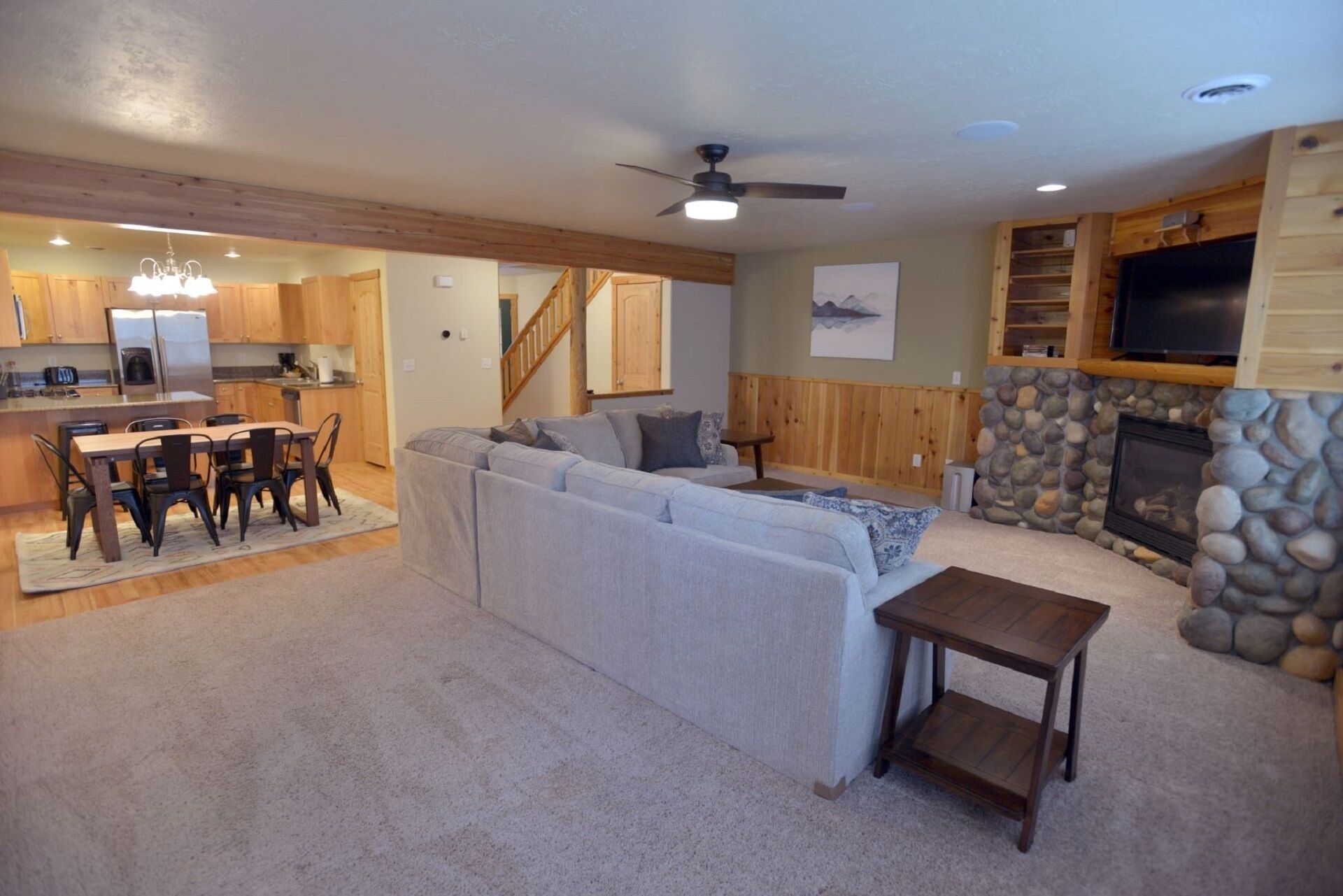 A spacious living area with a sofa, a dining table, and a stone fireplace.