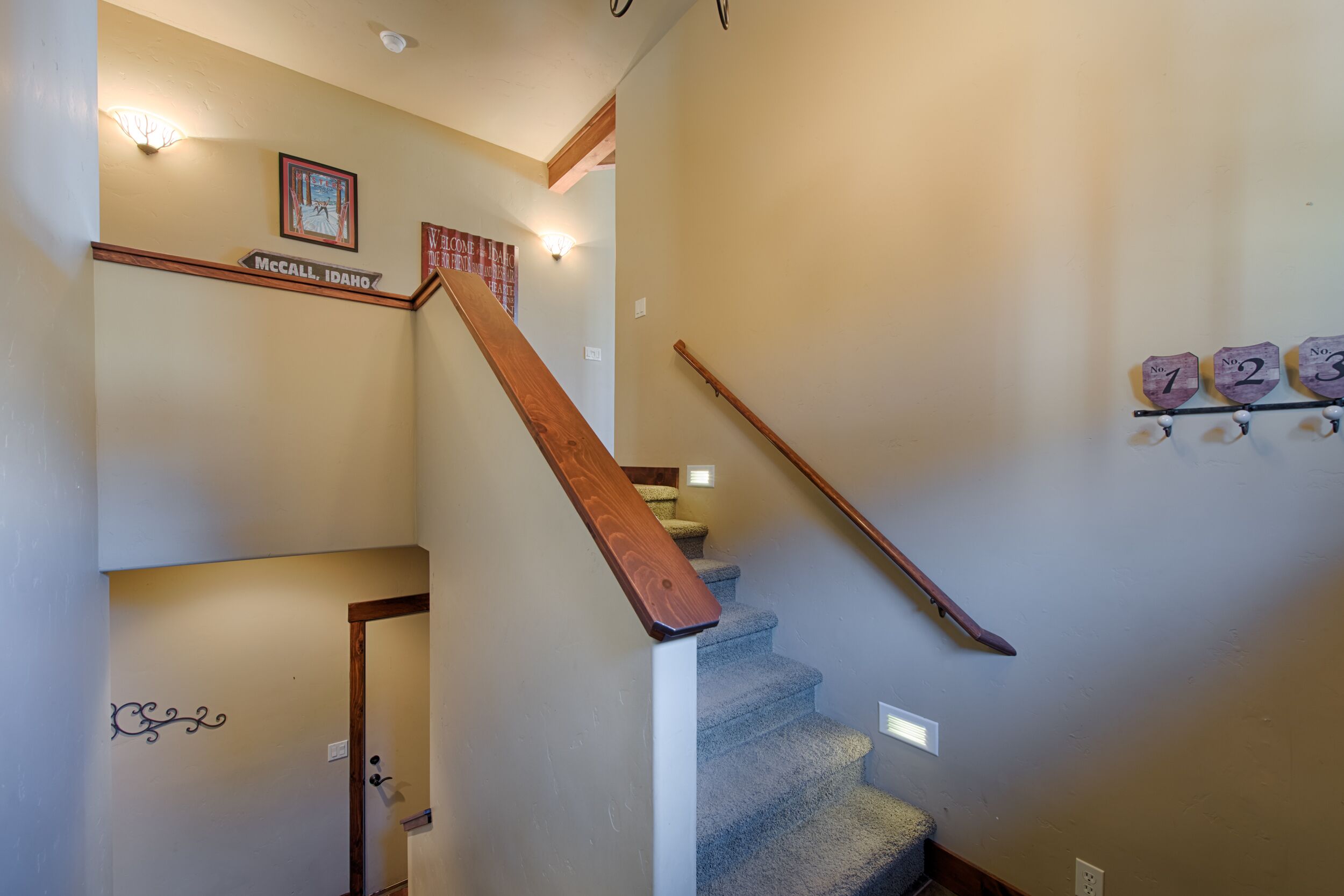 A staircase with wooden handrails, a welcome sign, and a wall-mounted number plate.