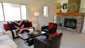 A living room with a stone fireplace, a white couch, a black leather chair, and a coffee table.