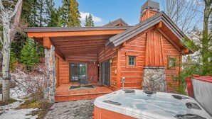 Eine Blockhütte mit Whirlpool, Steinwänden und einer Holzterrasse.