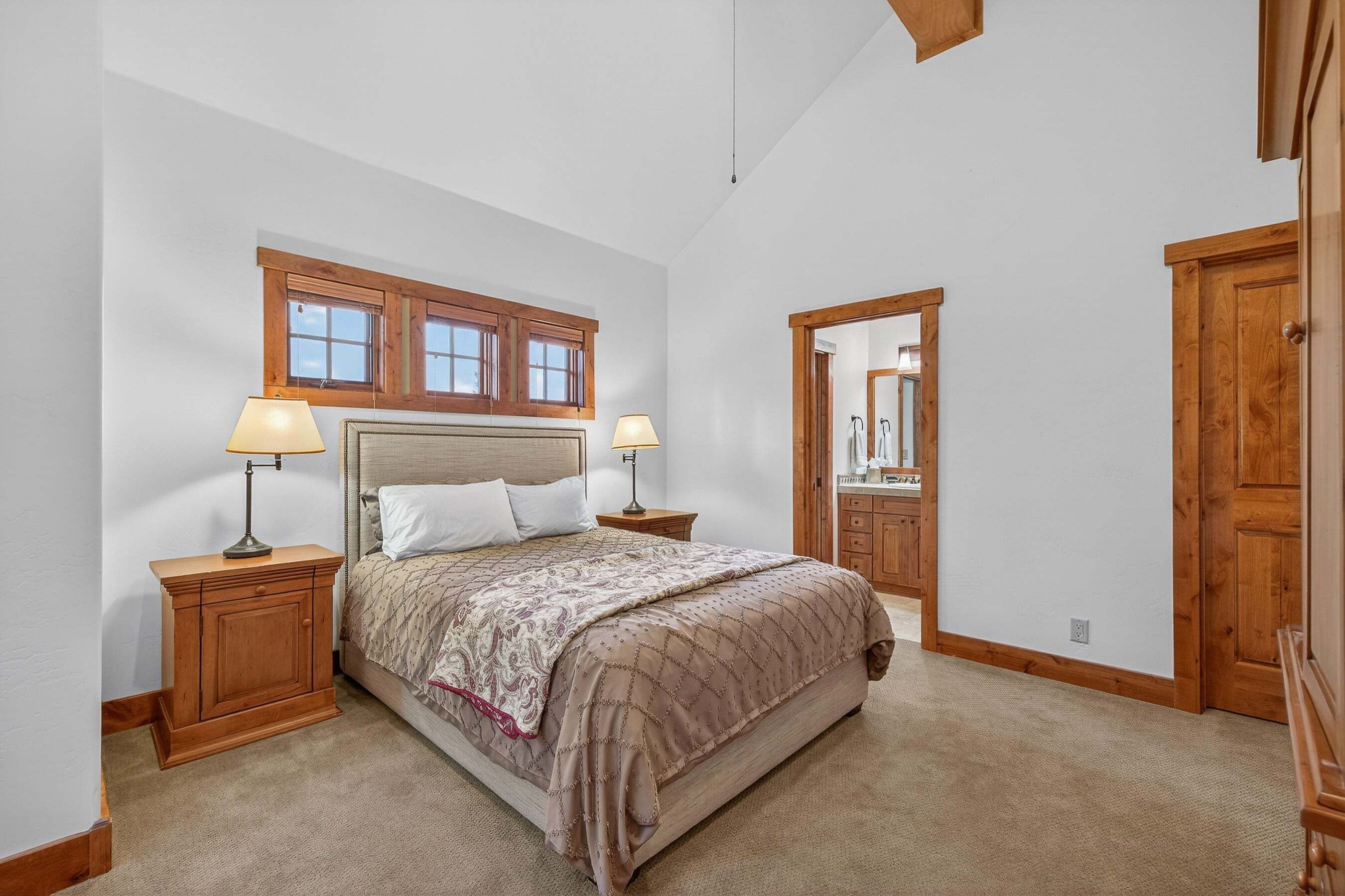 A bedroom with a bed, two bedside tables, a nightstand, a wooden wardrobe, and a mirror.