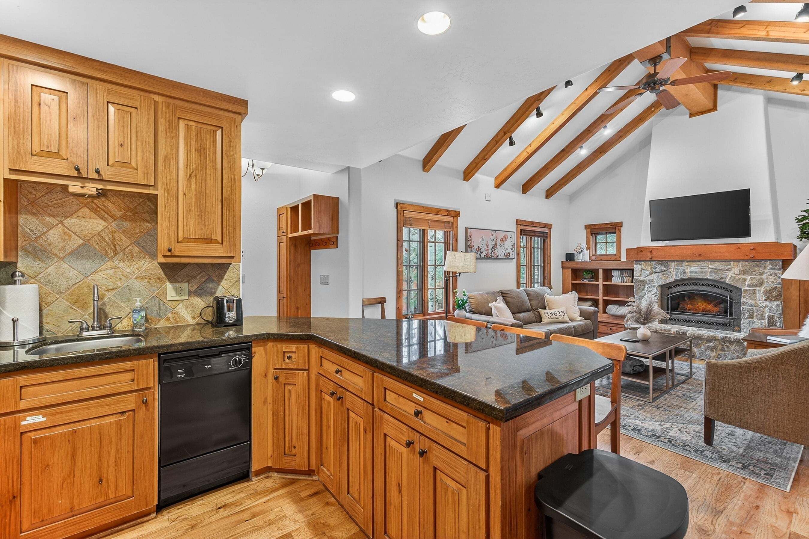 A kitchen with wooden cabinets, a dishwasher, and a stone backsplash.