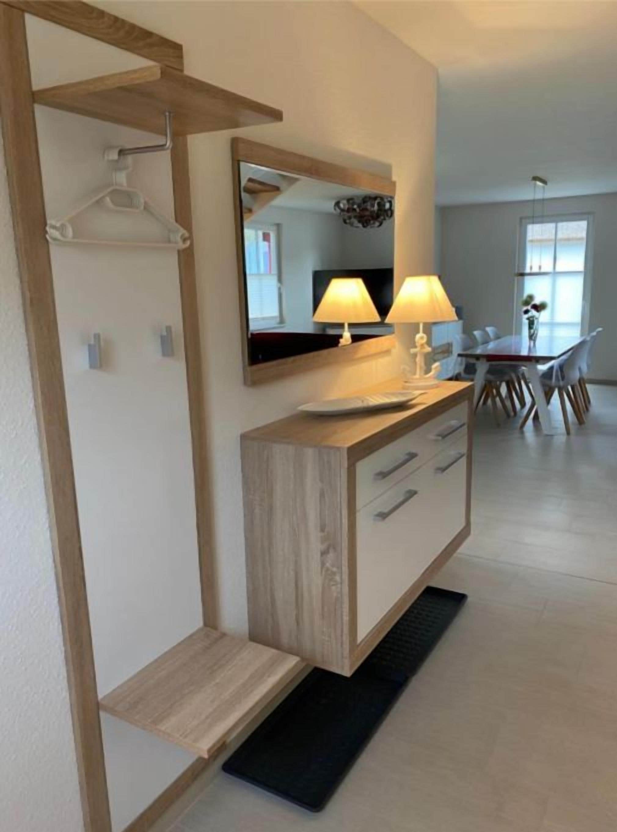 Une salle de bain moderne avec un meuble-lavabo en bois, un miroir et deux lampes fixées au mur.