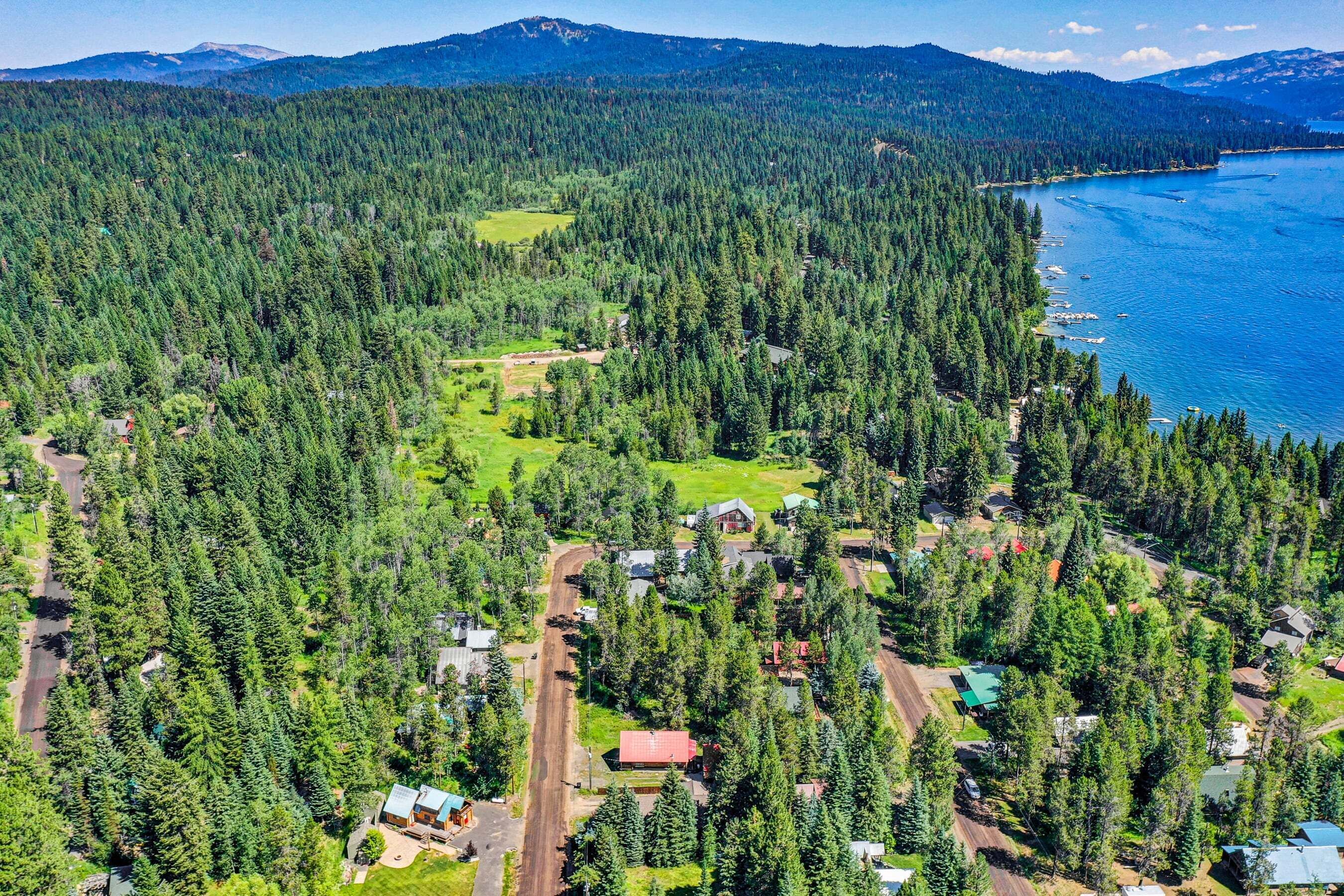Vista aérea de uma área arborizada com um pequeno conjunto de edifícios perto de um lago.