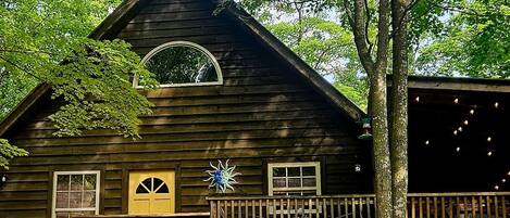 A wooden cabin with a triangular roof, a circular window, and a decorative sun ornament.