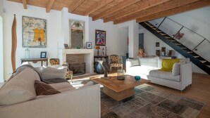 A spacious living room with a fireplace, a staircase, and a large painting on the wall. - Arte - Artist villa in the heart of la Noue (Sainte-Marie-de-Ré)