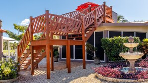 A wooden staircase leading to a covered area with a red umbrella, surrounded by gravel and potted plants. - The Luxury Poolhouse, Casa 2 at Casa de Shelley   Corozal, Belize (Ranchito, Corozal)