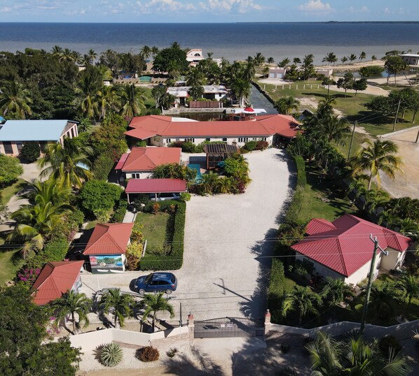 An aerial view of a resort with multiple buildings, a swimming pool, and a beach in the background.