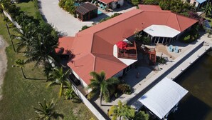 An aerial view of a resort with multiple buildings, including a large structure with a red roof and a smaller building with a blue roof. - The Luxury Poolhouse, Casa 2 at Casa de Shelley   Corozal, Belize (Ranchito, Corozal)