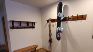 A room with a wooden bench, a wall-mounted ski rack, and a bench with a black mat. - Mountain Side Forest Retreat - Hot Tub!! - 1br 1ba <3beds> (Anchorage)