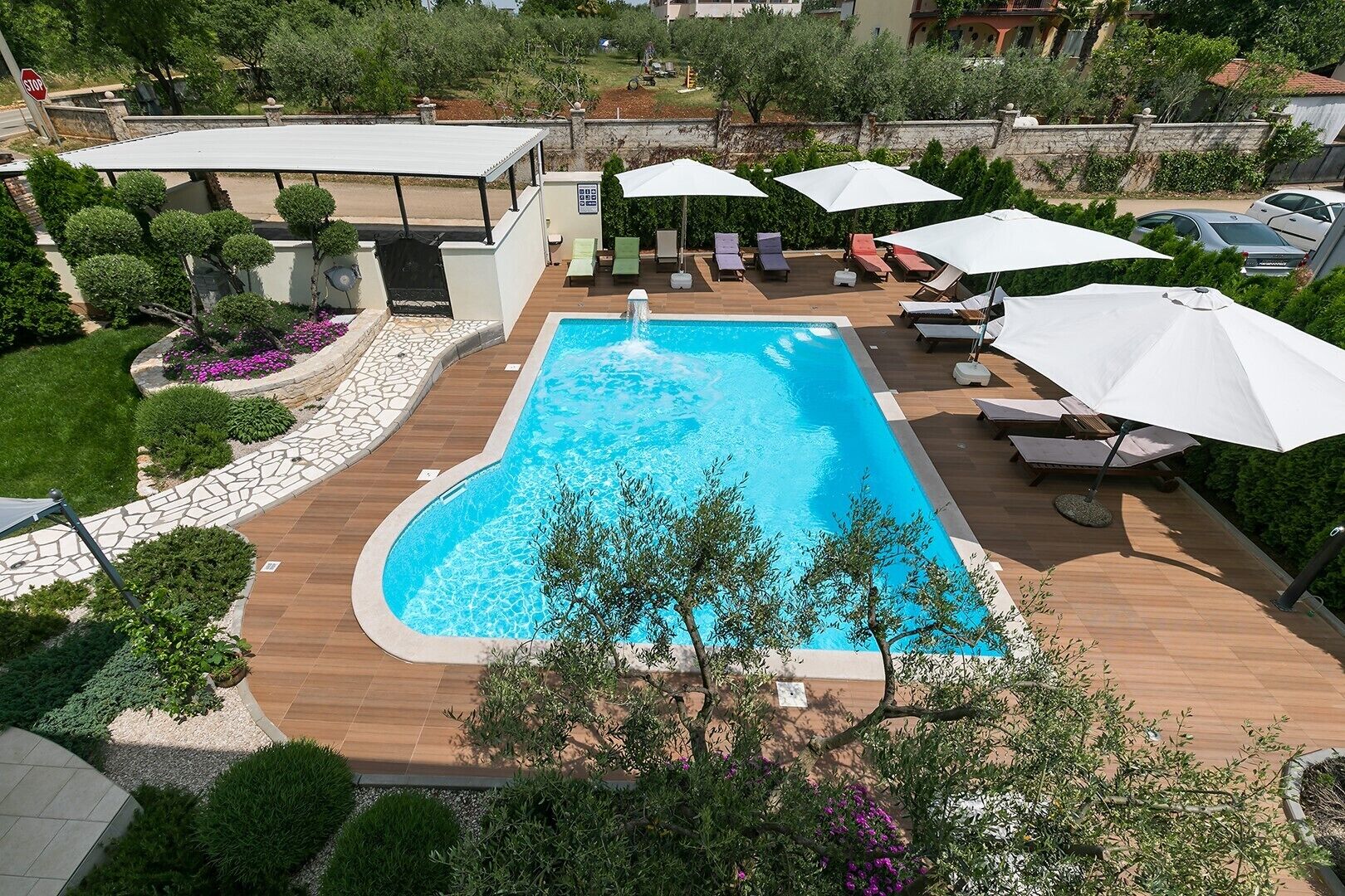 Une piscine rectangulaire entourée d’une terrasse en bois, agrémentée de plusieurs chaises longues et de parasols.