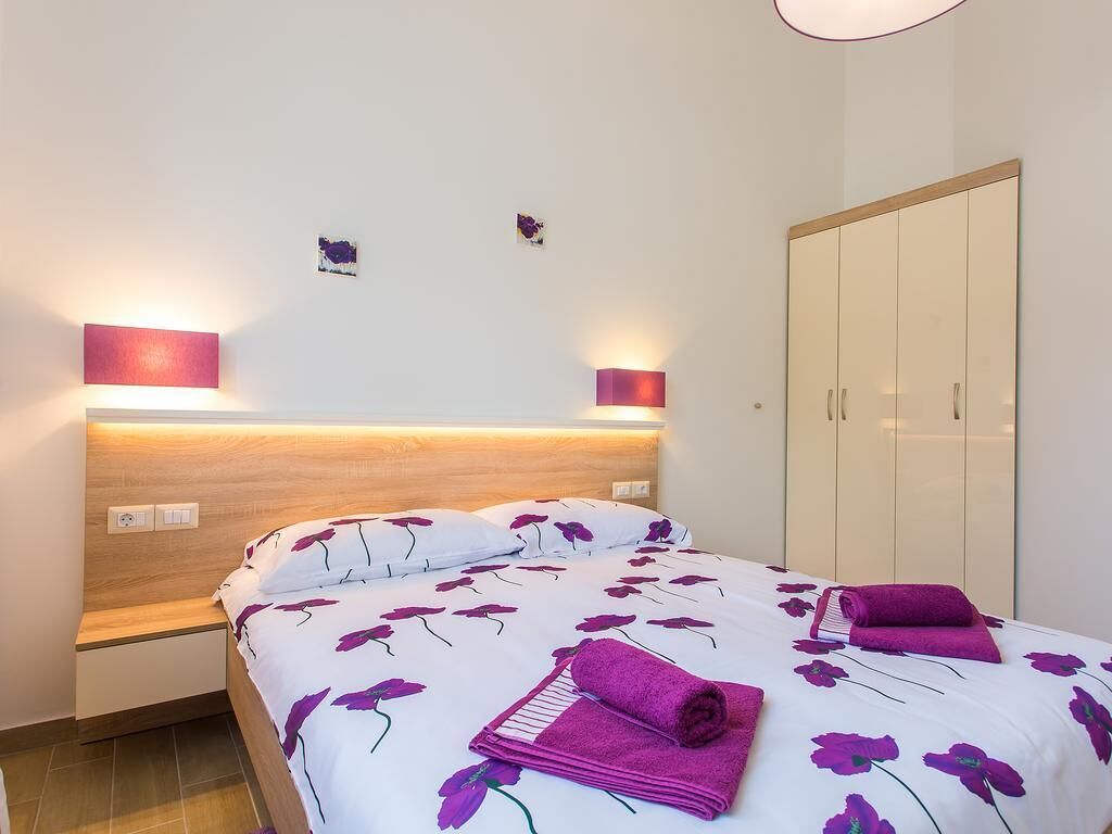 Une chambre à coucher comprenant un lit, des tables de chevet, une armoire et des lampes fixées au mur.