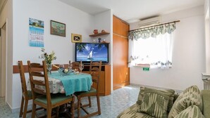 A living room with a television, a dining table with chairs, a sofa, and a window with curtains. - Popular fully equipped modern one bedroom apartment in a top location in Porec near the beach (Porec)