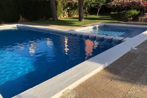 Ein rechteckiger Swimmingpool mit weißem Rand und einer mit Fliesen belegten Liegefläche.