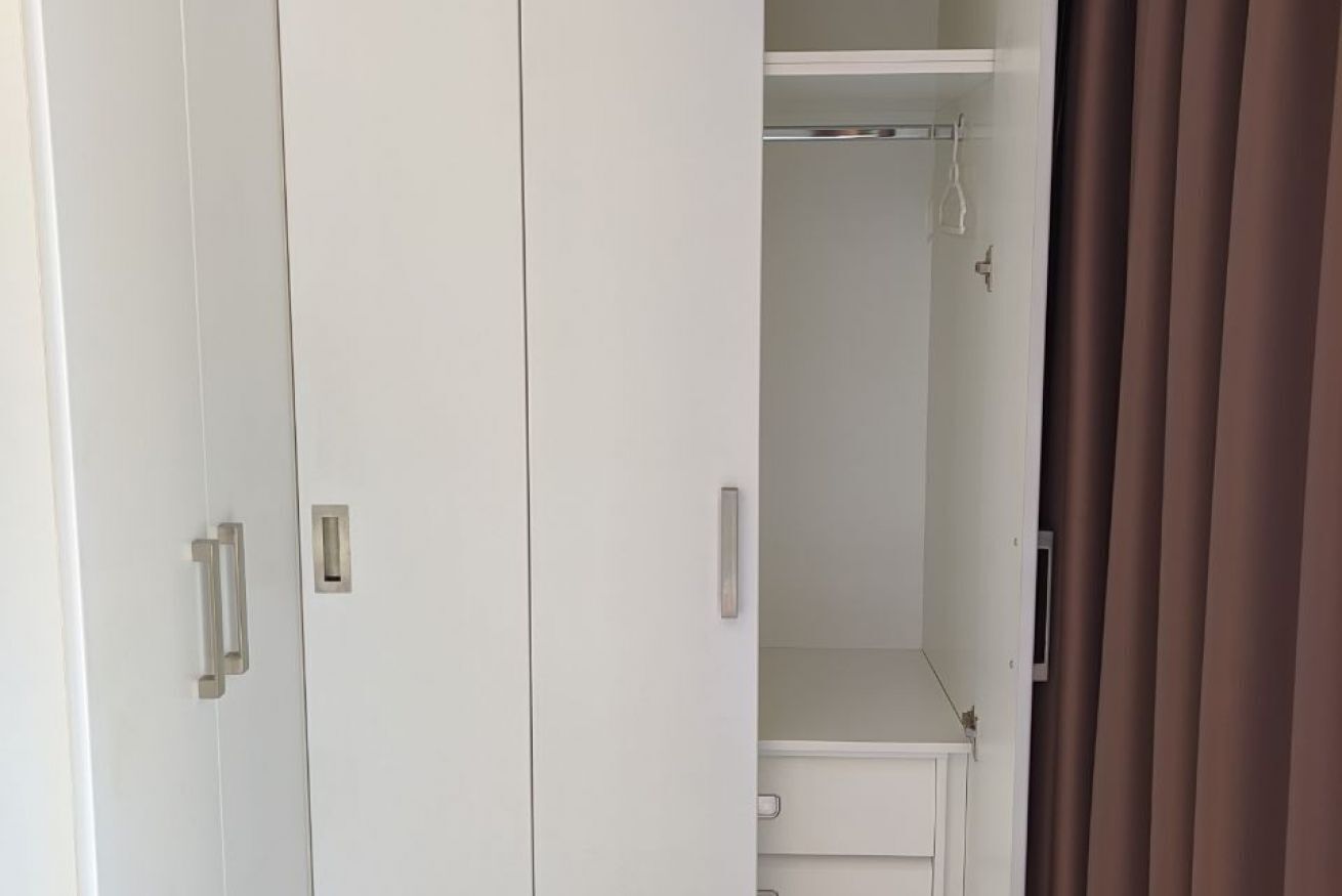 A white wardrobe with two handles and a shelf above it.