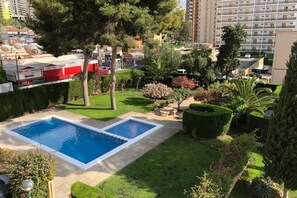 Un quartier résidentiel doté d’une piscine, entourée de pelouses et d’arbres bien entretenus.