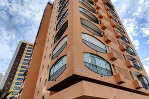 Un edificio alto y naranja con varios balcones y ventanas.