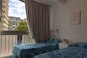 Un dormitorio con dos camas, una ventana con cortinas, una lámpara de pared y una cita motivacional.