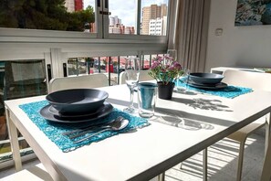 Una mesa de comedor dispuesta con platos, cuencos, cubiertos y una planta en maceta.