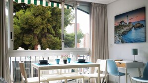 A modern room with a dining table, chairs, a desk, and a painting of a lighthouse. - SAN ANGELO Levante beach apartments (Benidorm)