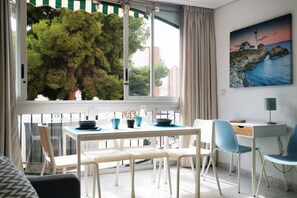 A modern room with a dining table, chairs, a desk, and a painting of a lighthouse.
