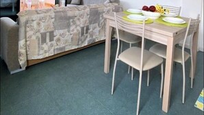 A compact living space with a dining area, a ceiling fan, and a view through a sliding glass door. - Apartment Ionian coast (Sant'Andrea Apostolo dello Ionio)