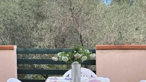 A patio table with a floral tablecloth, two white plastic chairs, and a vase with white flowers. - Apartment Ionian coast (Sant'Andrea Apostolo dello Ionio)
