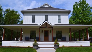 A two-story house with a front porch, a central door, and a symmetrical window arrangement. - Beautifully renovated 3,800 sq ft house between 2 federal lakes  (Lyndon)