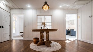 A spacious room with a wooden floor, a round table with a vase, and a hanging light fixture. - Beautifully renovated 3,800 sq ft house between 2 federal lakes  (Lyndon)