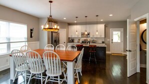 Una cocina moderna con armarios blancos, una mesa de comedor de madera y taburetes de bar.
