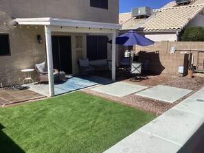 A covered patio area with outdoor furniture, a blue umbrella, and a small lawn. - Clean Family Home / Resort like outdoor space (Phoenix)