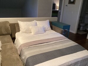 A bedroom with a bed, a sofa, and a small table.
